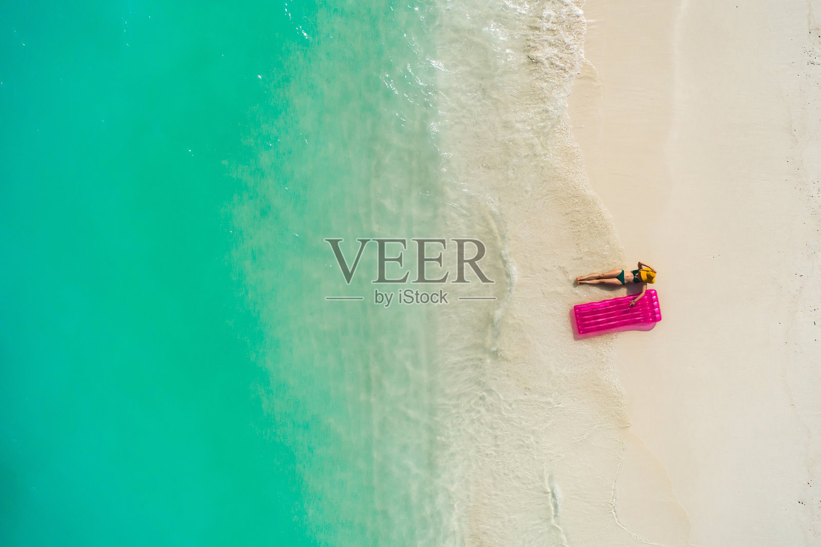 夏日假日的时尚概念——晒黑的女孩戴着太阳帽在沙滩上白沙滩上拍摄。俯视图从无人机。鸟瞰躺在马尔代夫海滩上晒太阳的苗条女人。照片摄影图片