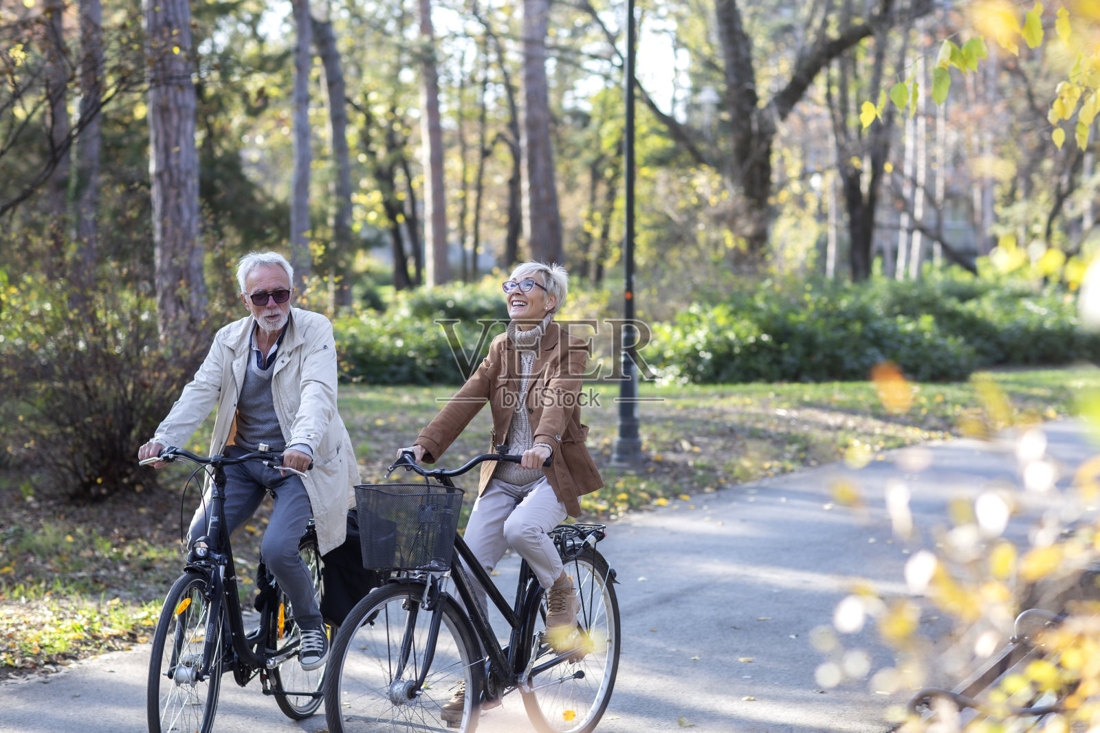 一对成熟的情侣在公园里骑自行车，面带微笑照片摄影图片