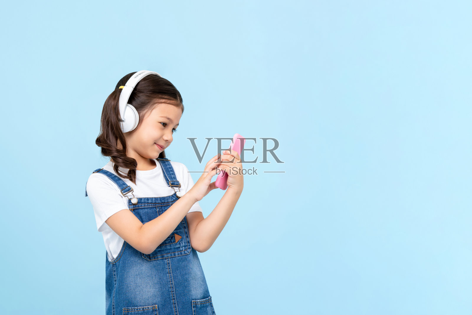 可爱的8岁小女孩戴着耳机听手机音乐照片摄影图片