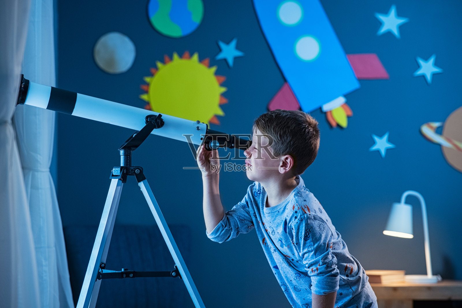 男孩晚上用望远镜看星星照片摄影图片