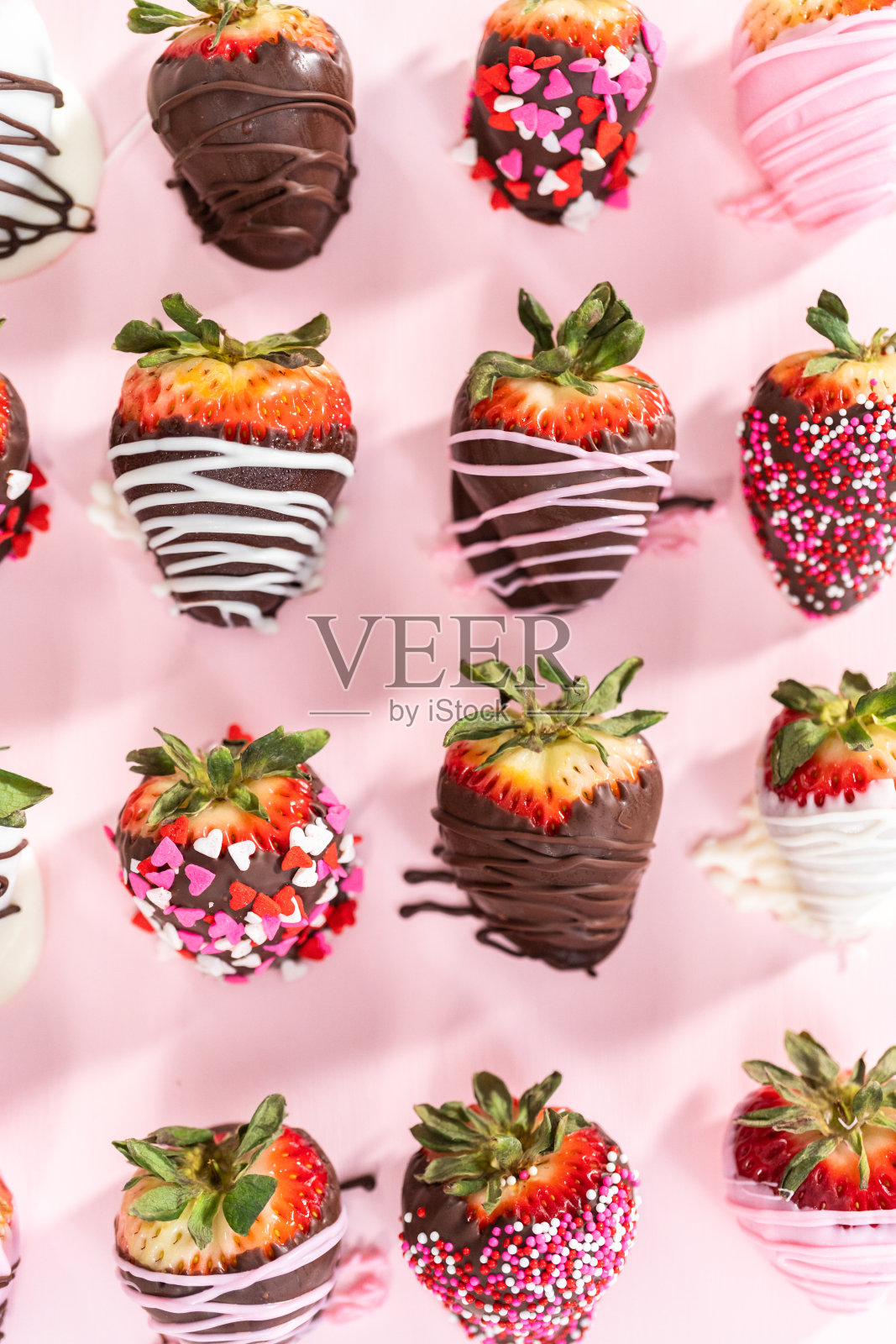 各种巧克力蘸草莓在粉红色的背景。照片摄影图片