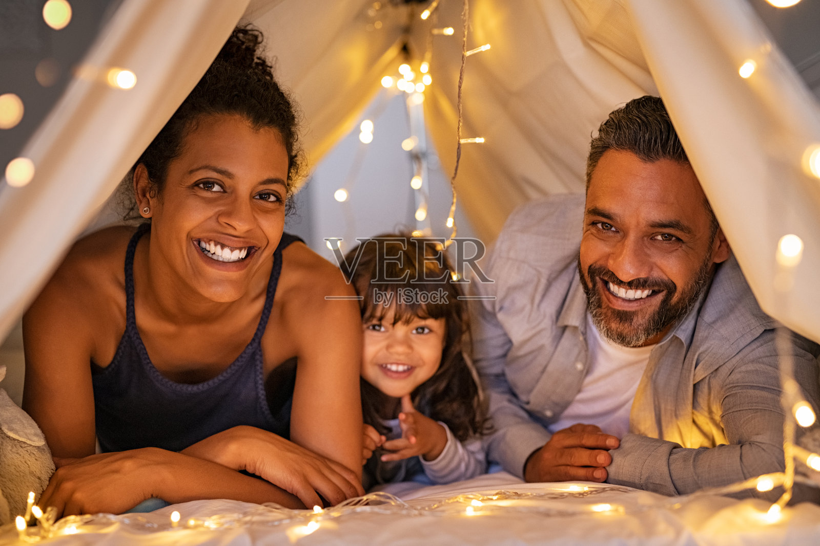 快乐的父母和女儿在舒适的帐篷里玩得开心照片摄影图片