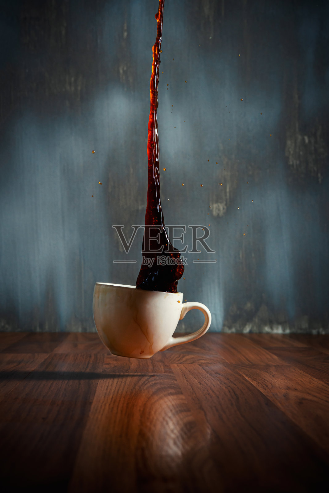 热咖啡杯洒在木地板上，咖啡水溅在深色的背景上照片摄影图片
