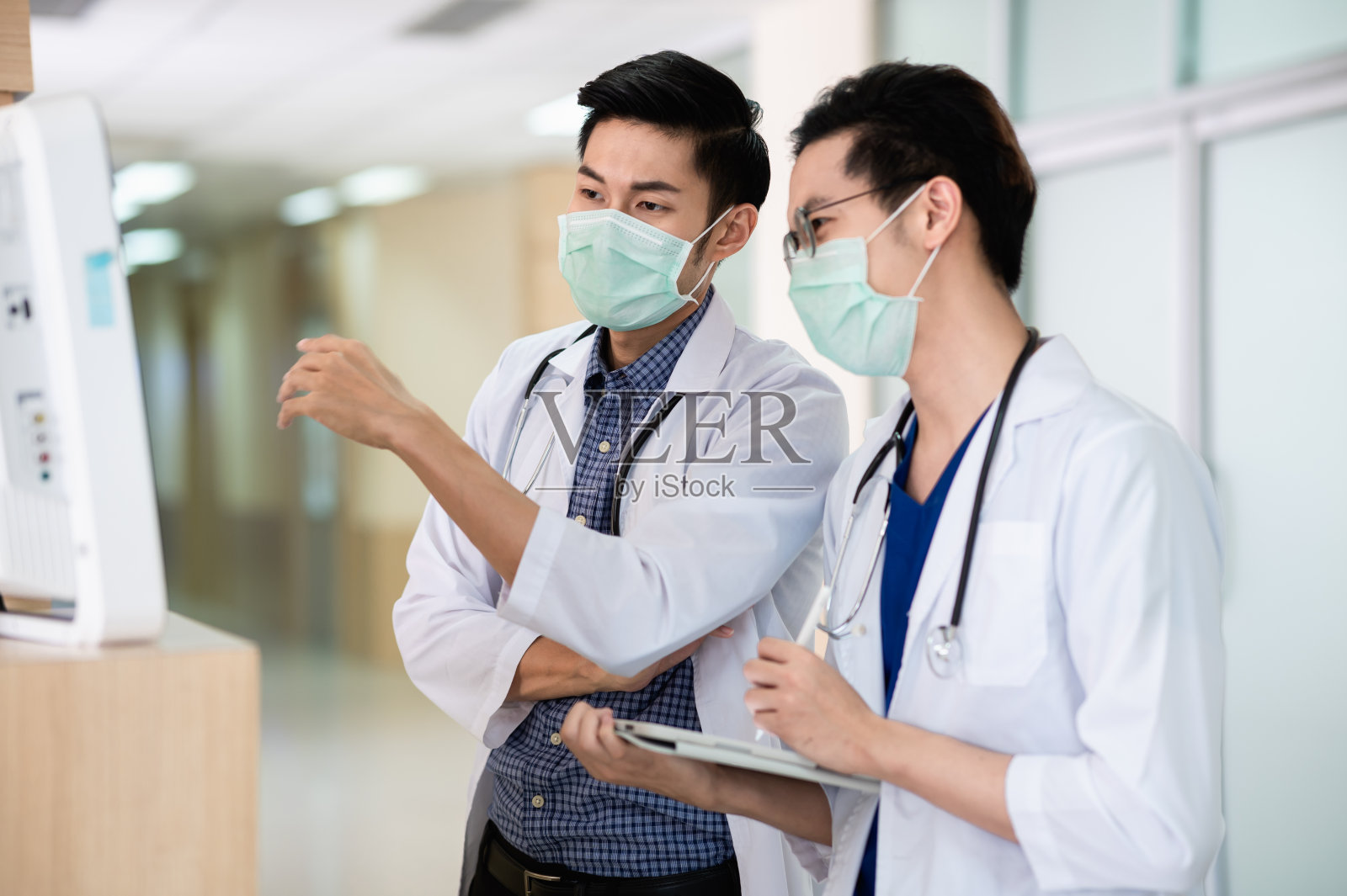 两位亚洲男性专业医生一边讨论和咨询病人的护理，一边在屏幕上查看病人的医疗报告，并记录在数字平板电脑上。医疗保健理念。照片摄影图片