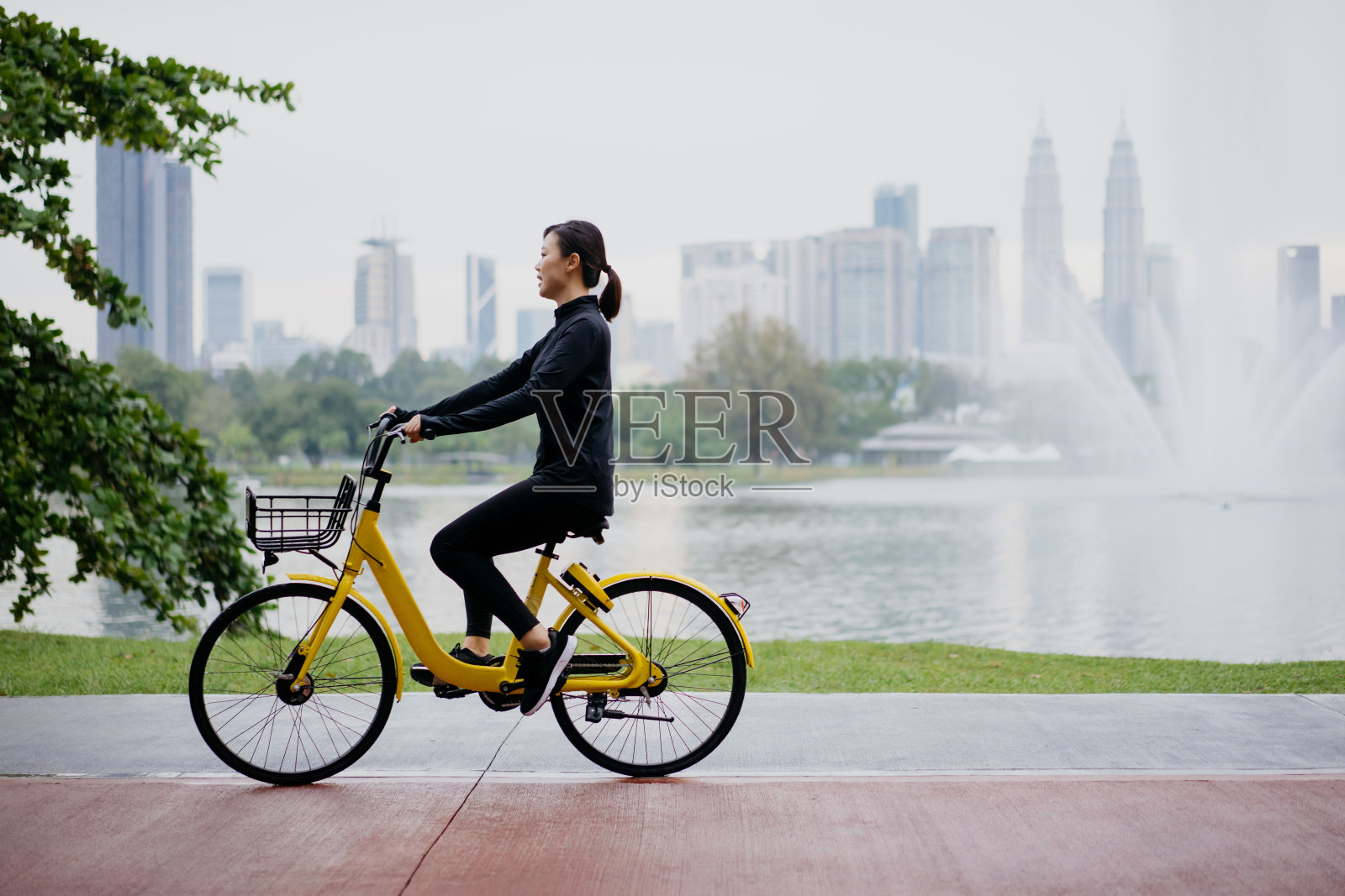 快乐的年轻亚洲女人在公园骑车照片摄影图片