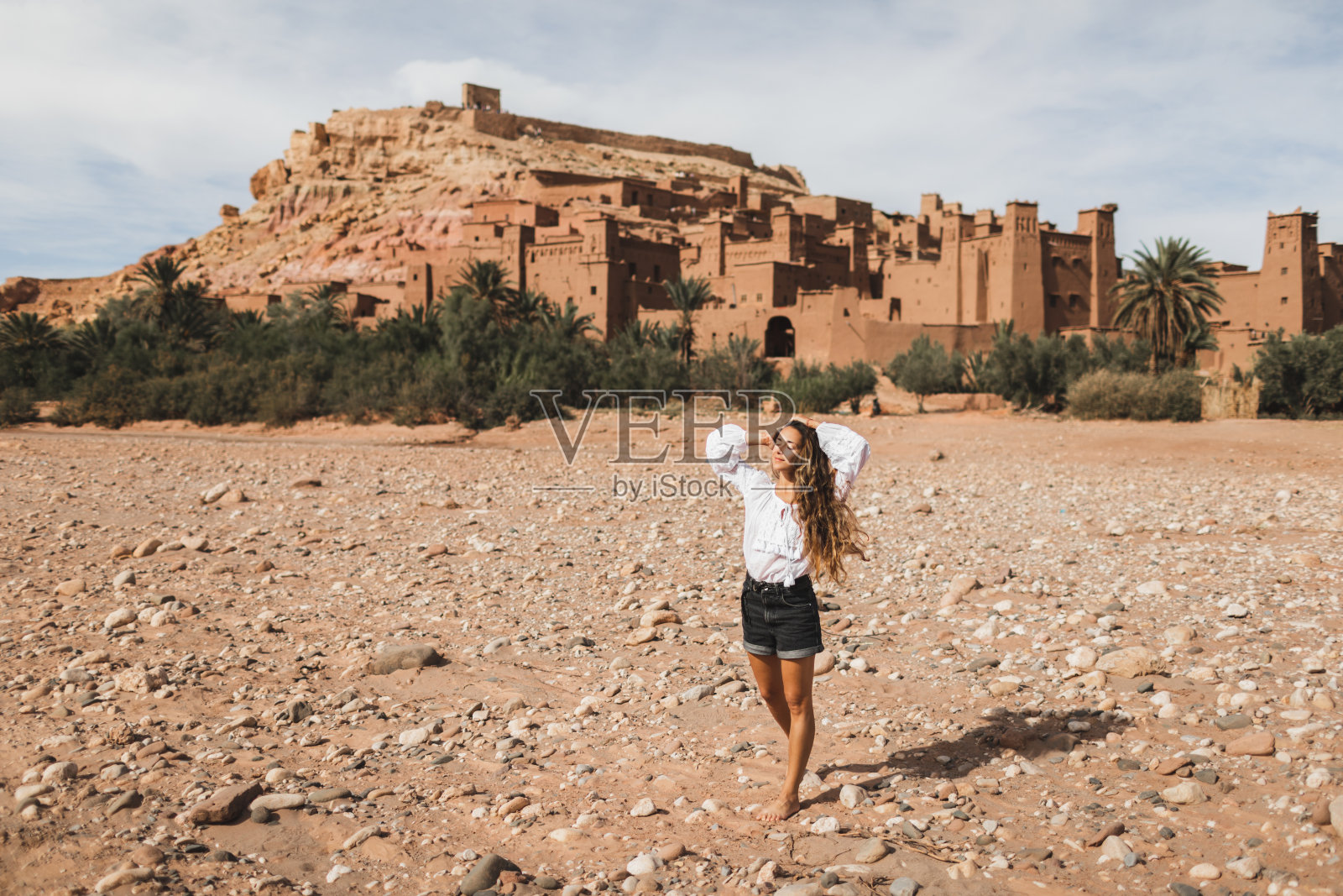 年轻的卷发女人东方人的外表走在卡斯巴艾特本哈杜的背景。去摩洛哥旅行，瓦尔扎扎特。暑期度假，旅游生活理念。照片摄影图片