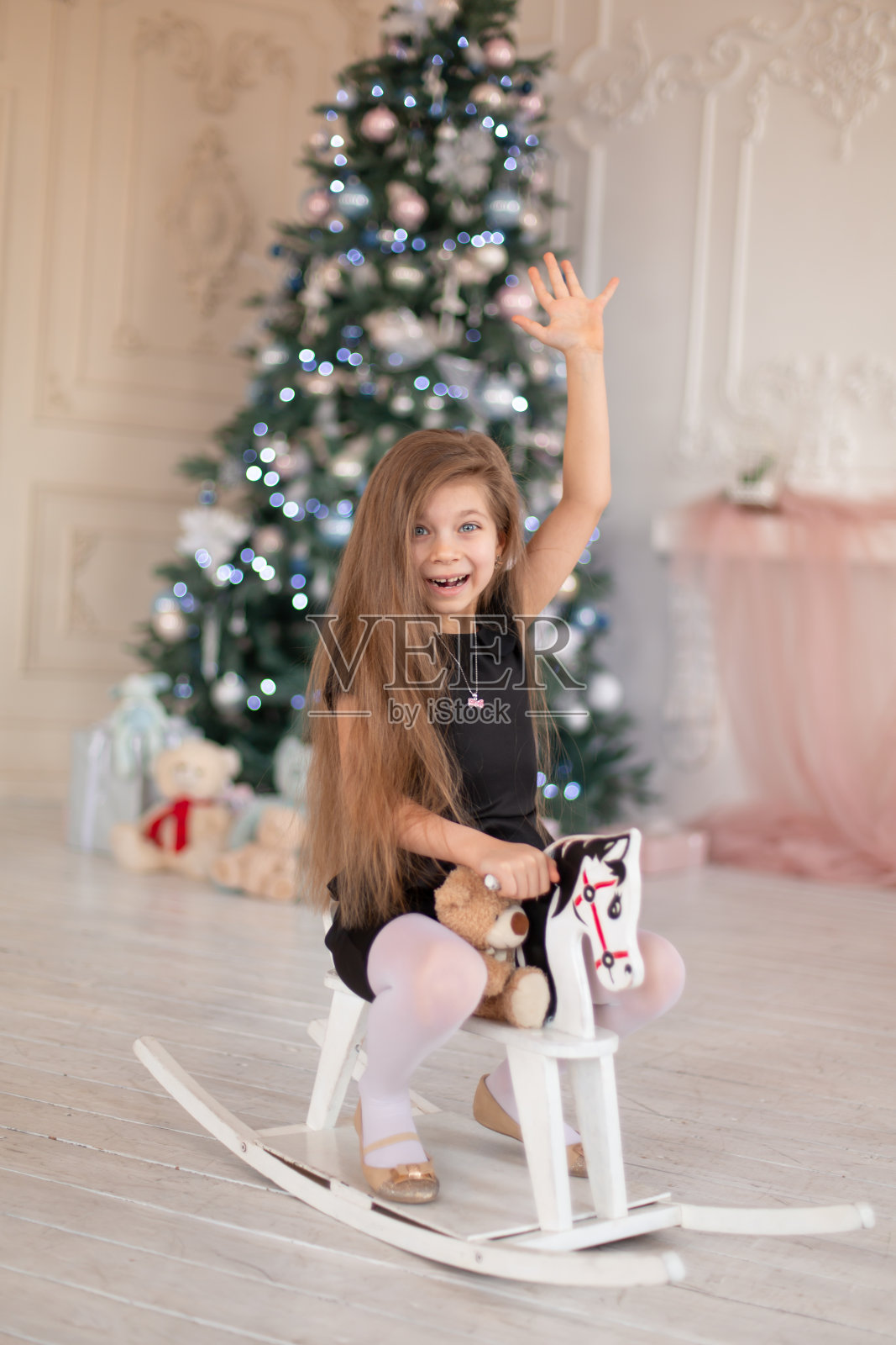 美丽的小女孩高兴的木制木马，圣诞老人的圣诞礼物照片摄影图片
