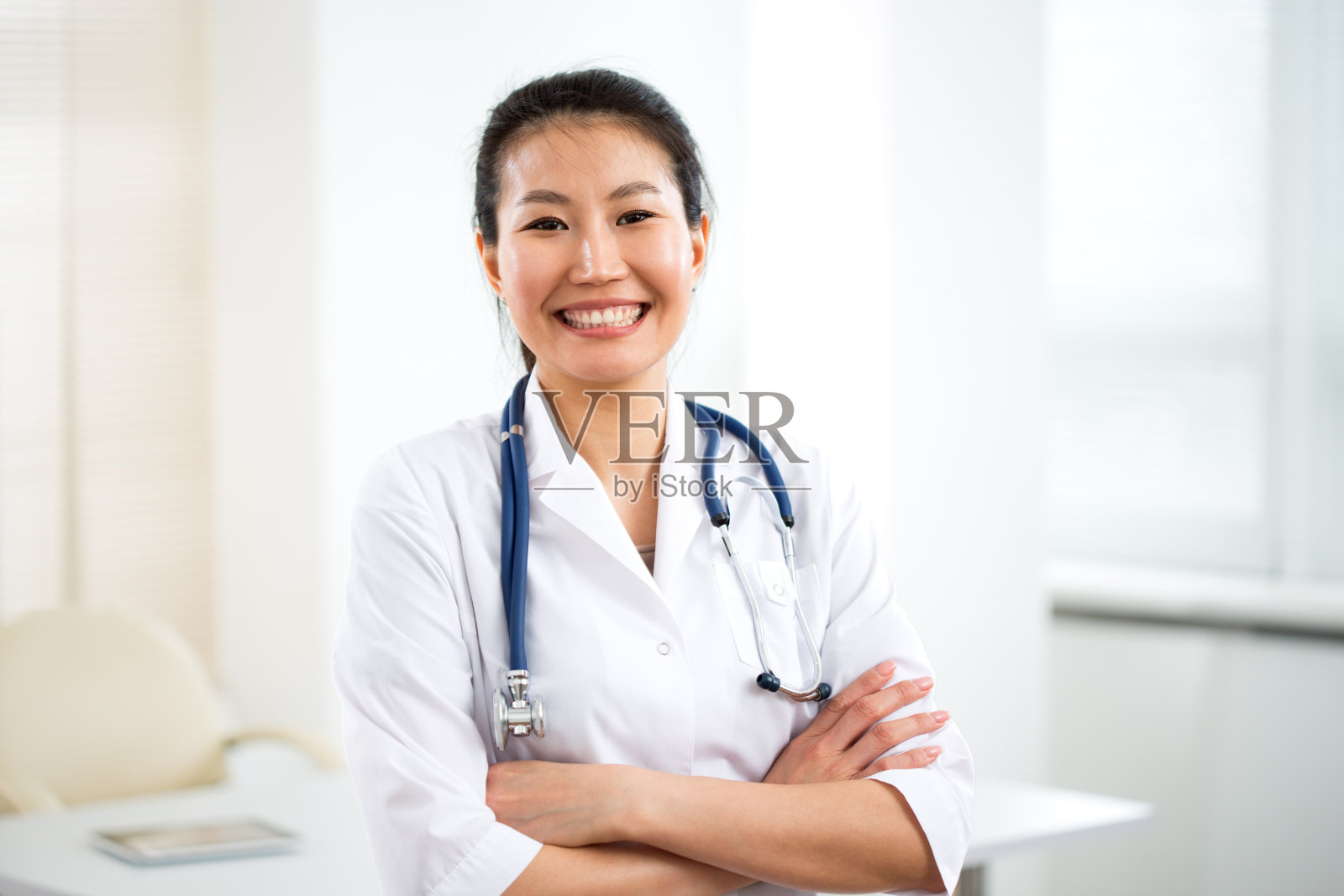 微笑的亚洲女医生的肖像在灰色的背景为您的文本。照片摄影图片