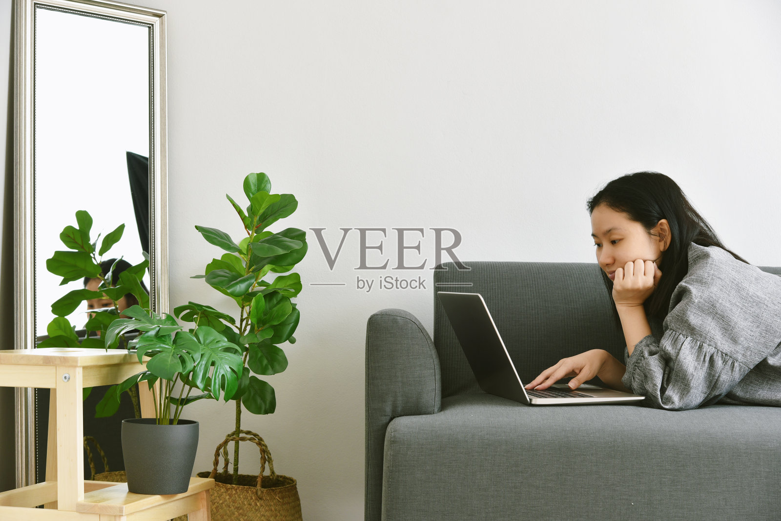 在家工作的妇女用笔记本电脑环绕着绿色的热带树木，人与自然，室内植物生长在客厅，用于室内空气净化和家居装饰。照片摄影图片