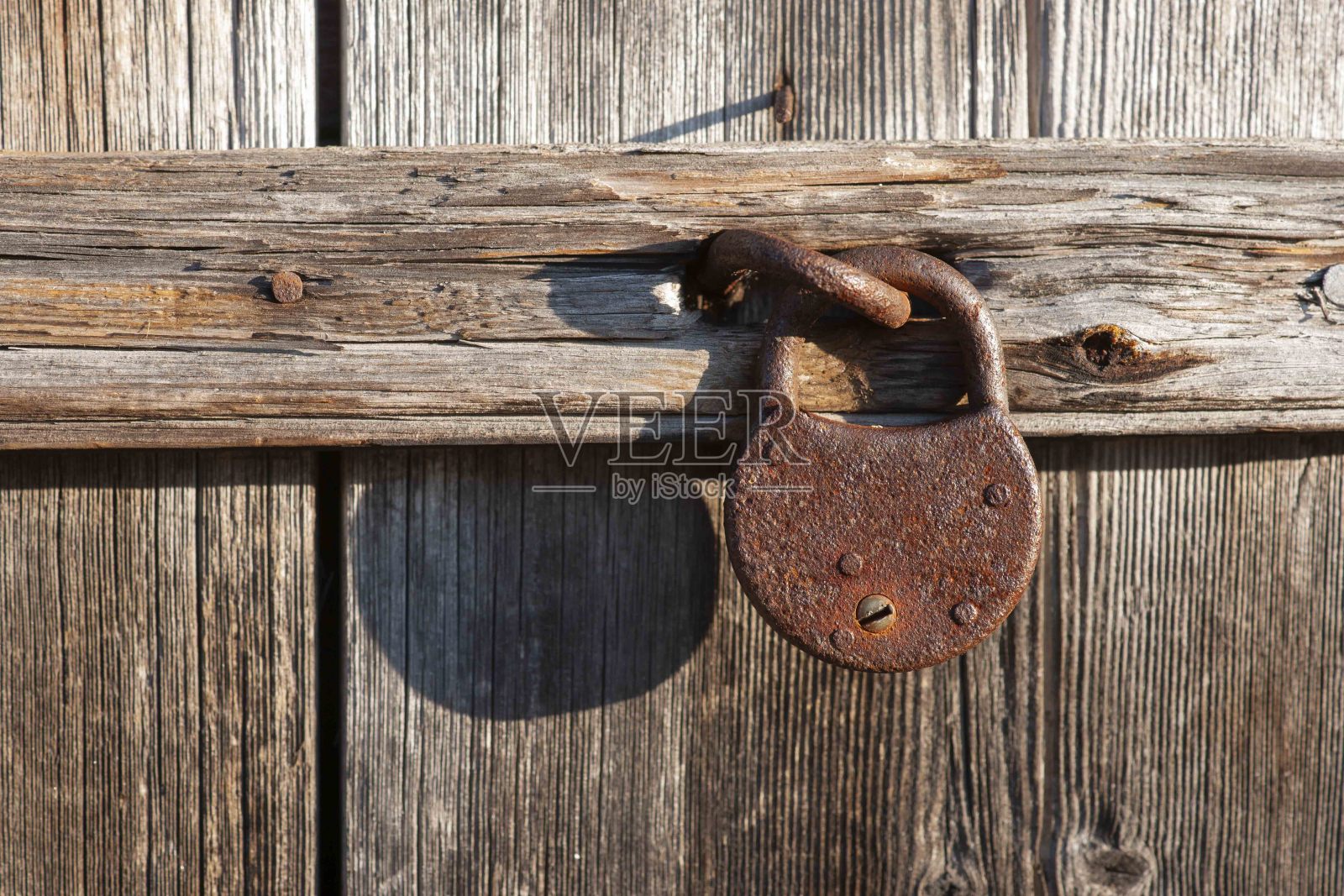 锈迹斑斑的挂锁挂在破旧风化的木门上照片摄影图片