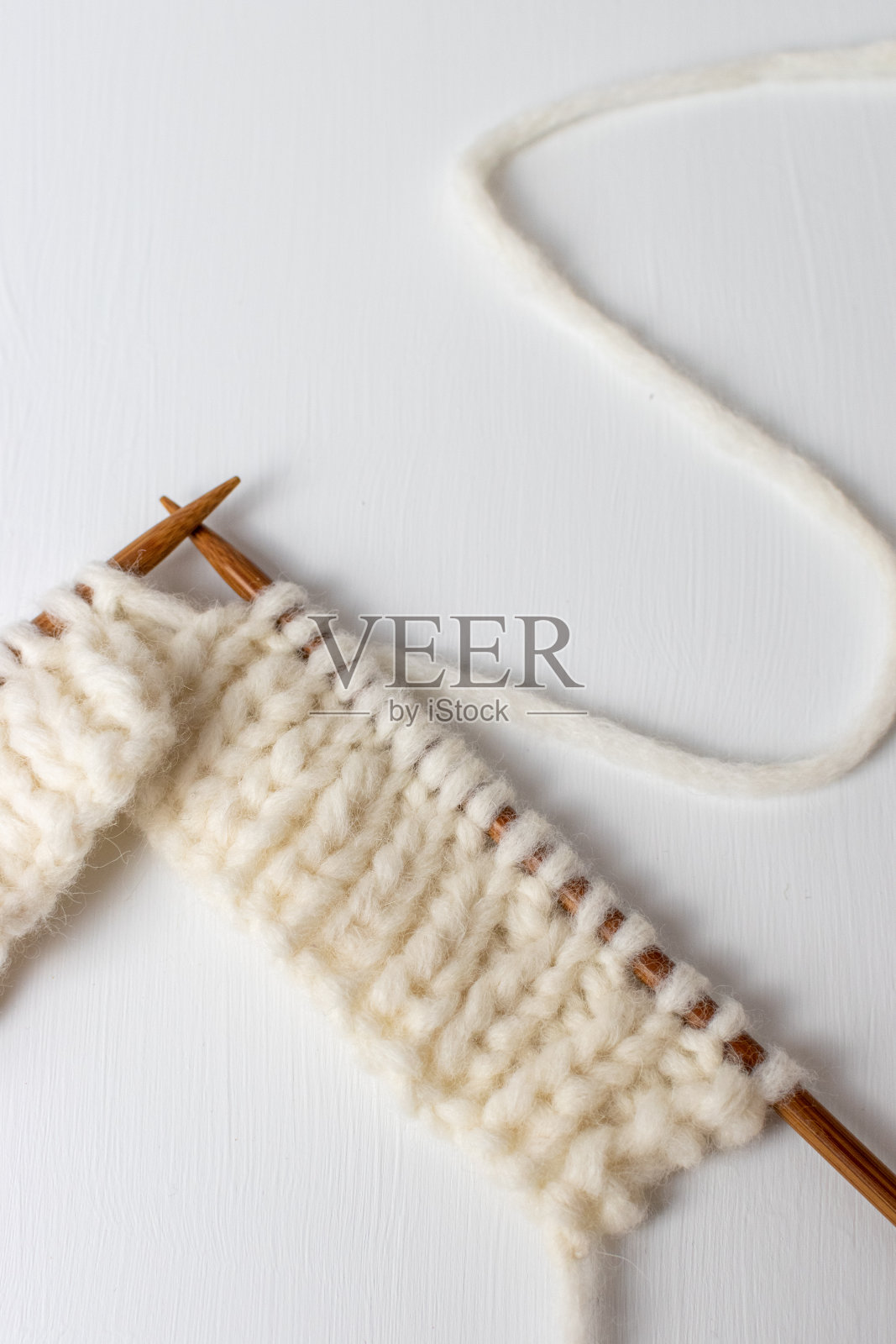 柔软厚实的羊毛在白色的背景和编织针照片摄影图片