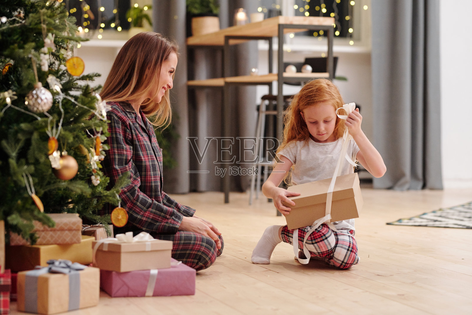 可爱的小女孩在拆礼品盒上的丝带，准备拿出圣诞礼物照片摄影图片