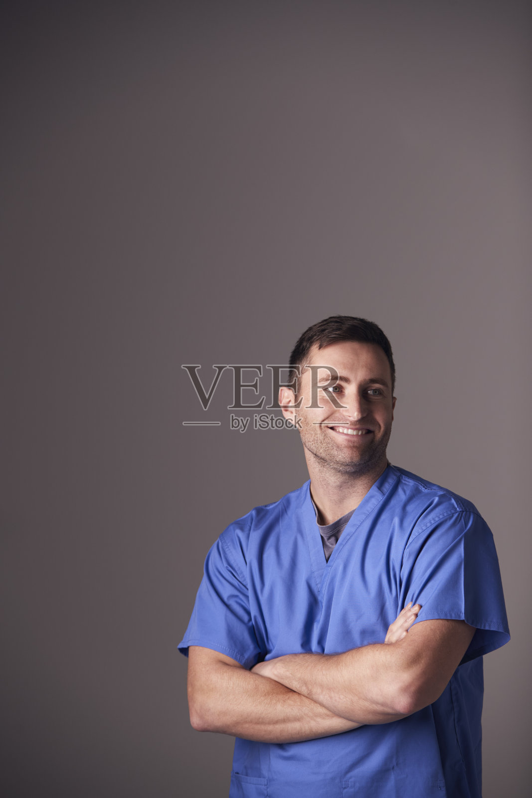 在灰色背景下，穿着手术服的男护士的工作室肖像照片摄影图片