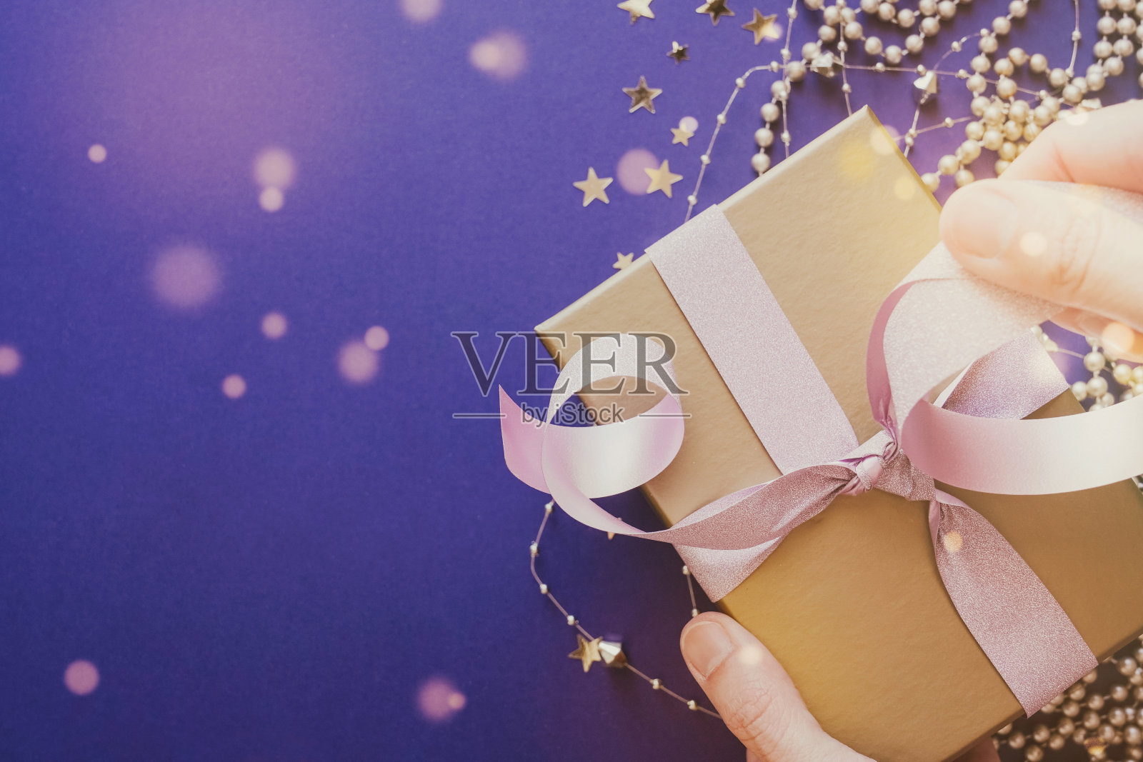 手打开金色礼盒与亮粉色丝带，节日假期圣诞新年2021背景照片摄影图片