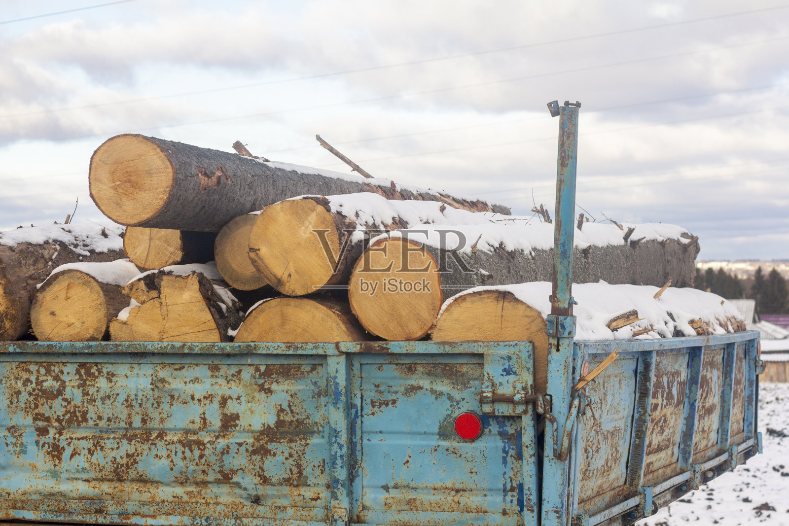 一辆旧车里埋在雪下的原木。准备冬天取暖用的柴火。照片摄影图片