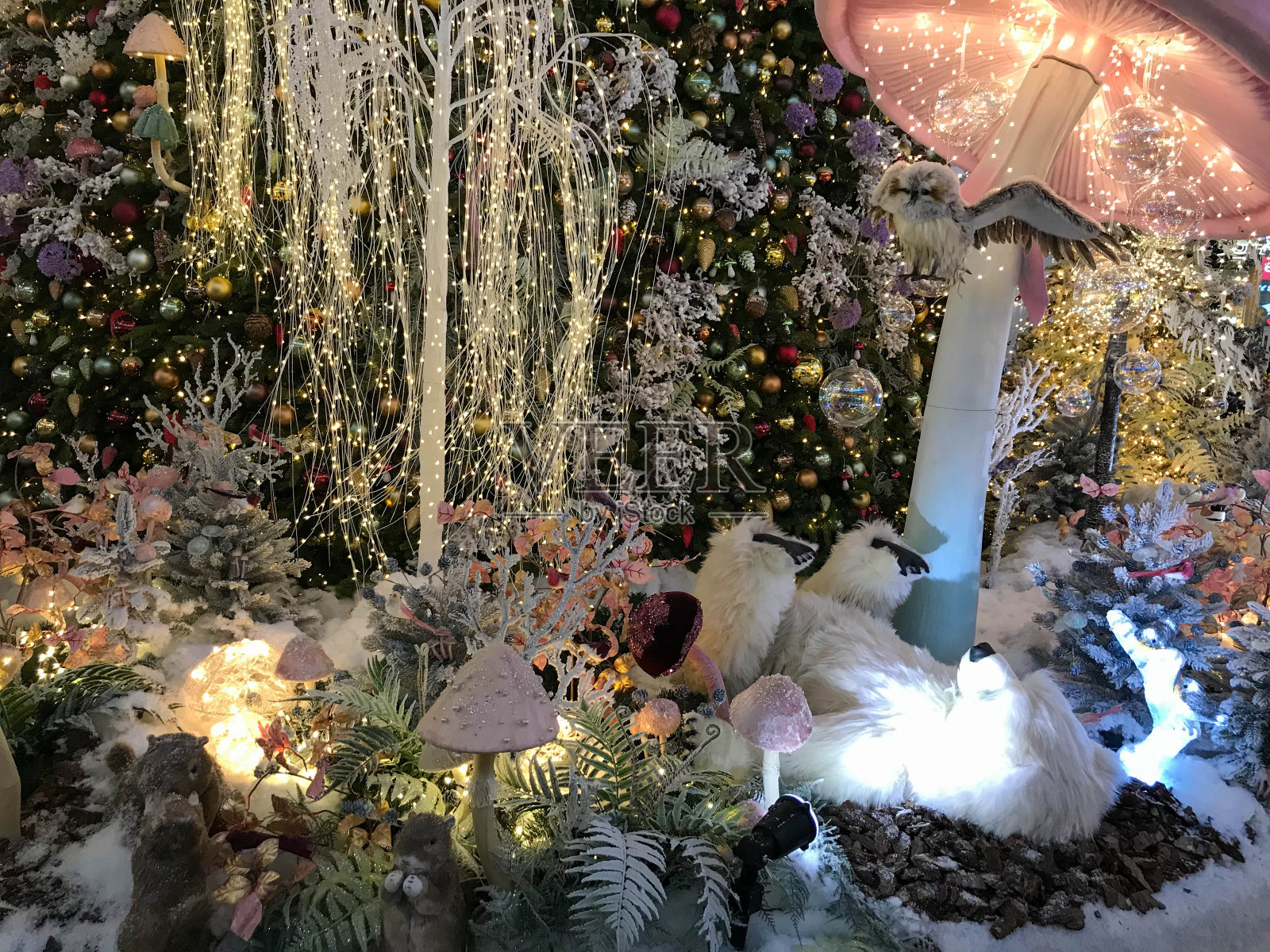 圣诞装饰品。一只玩具北极熊躺在一个五颜六色的蘑菇下，移动着它的爪子。她旁边是五颜六色的蘑菇。给孩子们的平安夜可爱的玩具照片摄影图片