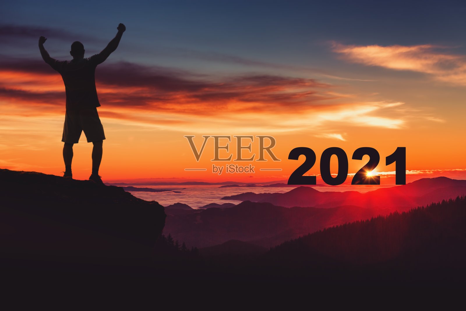 一名男子在山顶边观看日出，边庆祝2021年。照片摄影图片