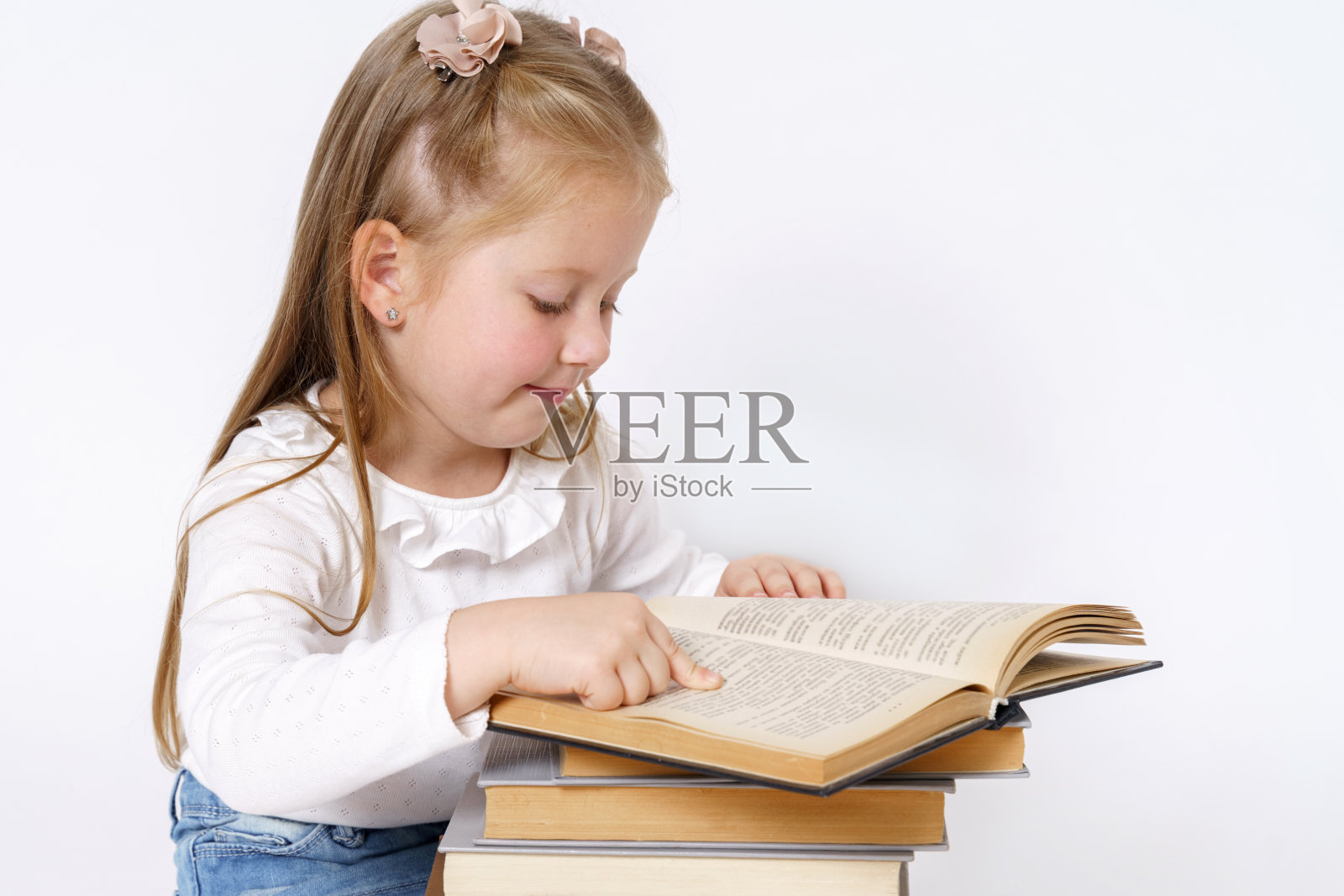 一个坐在书旁边的十几岁女孩的肖像。孤立的白色背景。照片摄影图片
