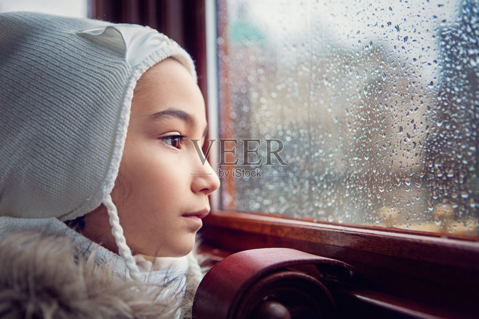 在一个下雨天，女孩透过窗户看照片摄影图片