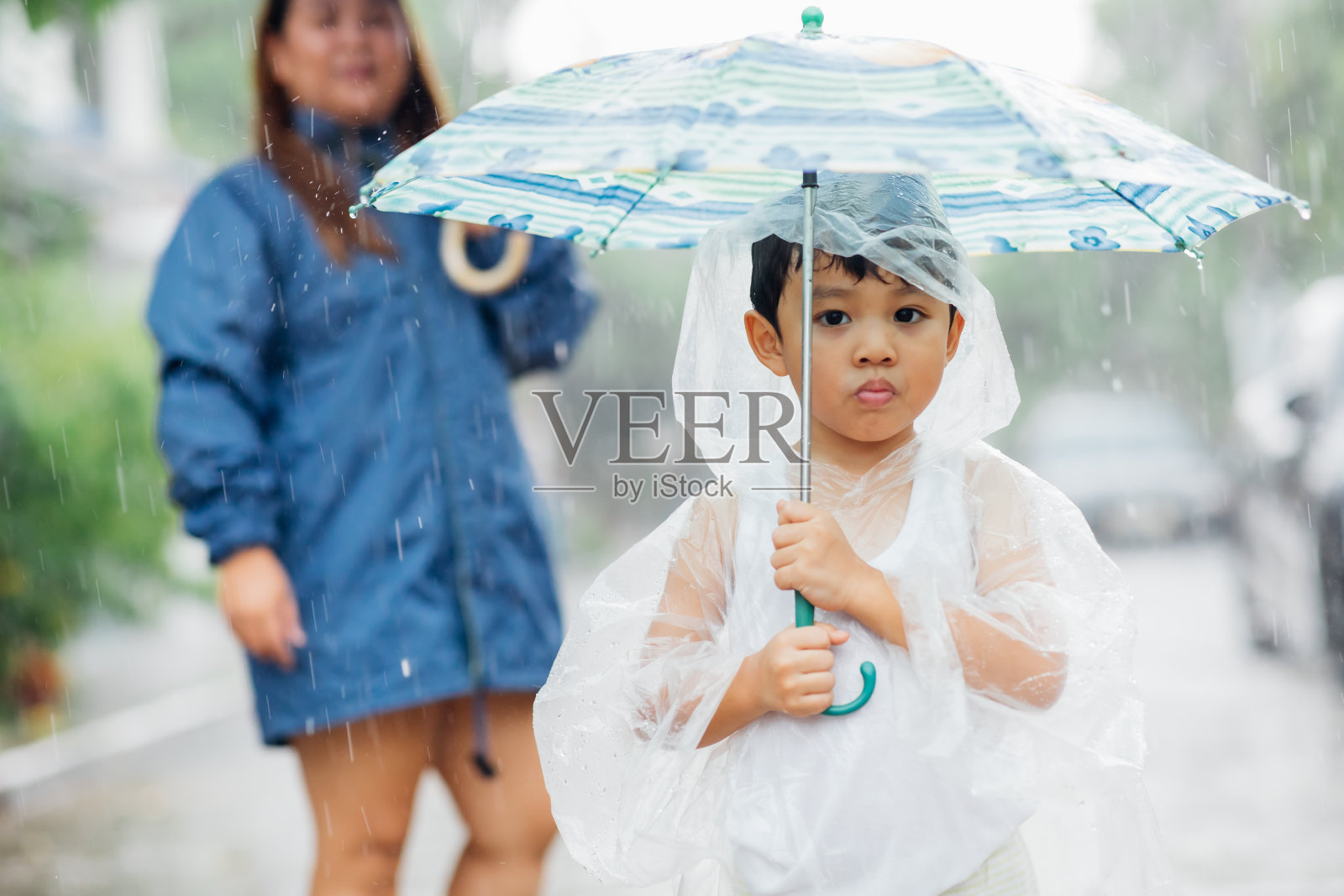 亚洲胖妈妈和儿子在雨中散步和玩耍照片摄影图片