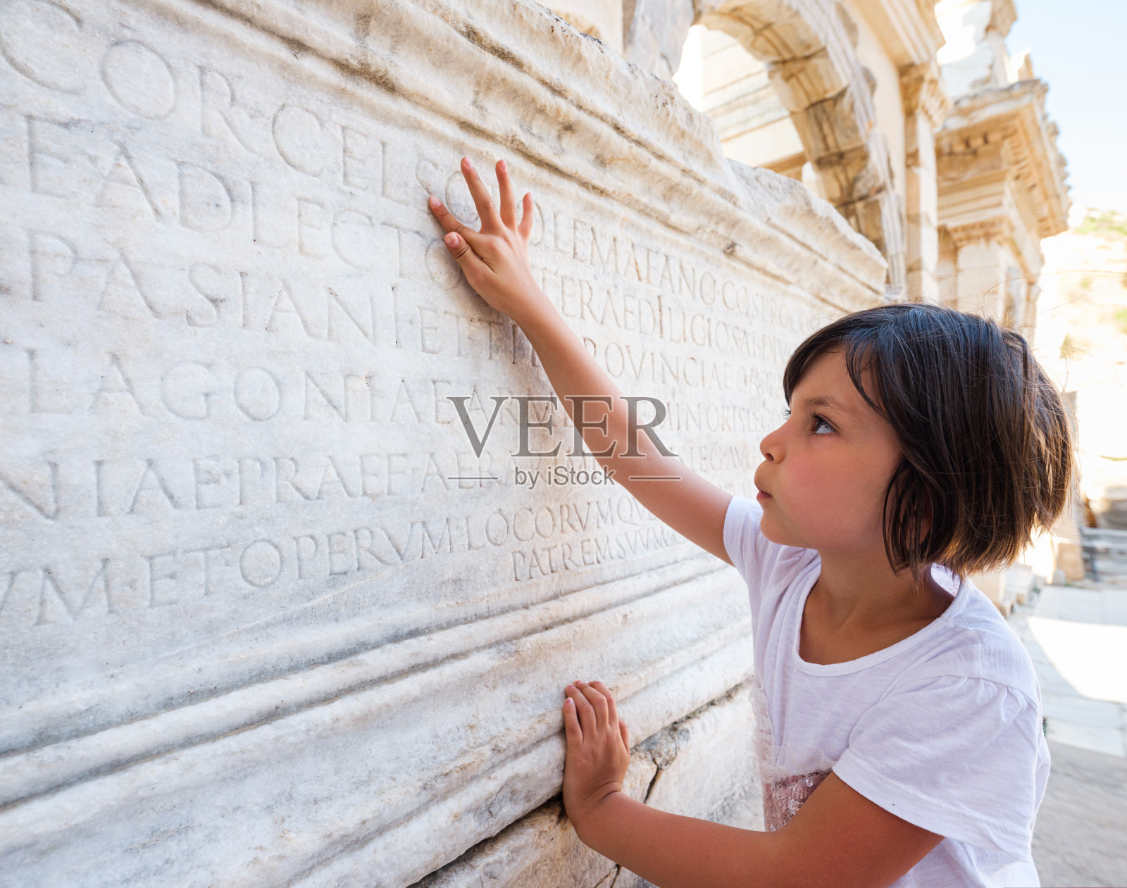 小女孩念着古代铭文中的字母，以弗所照片摄影图片