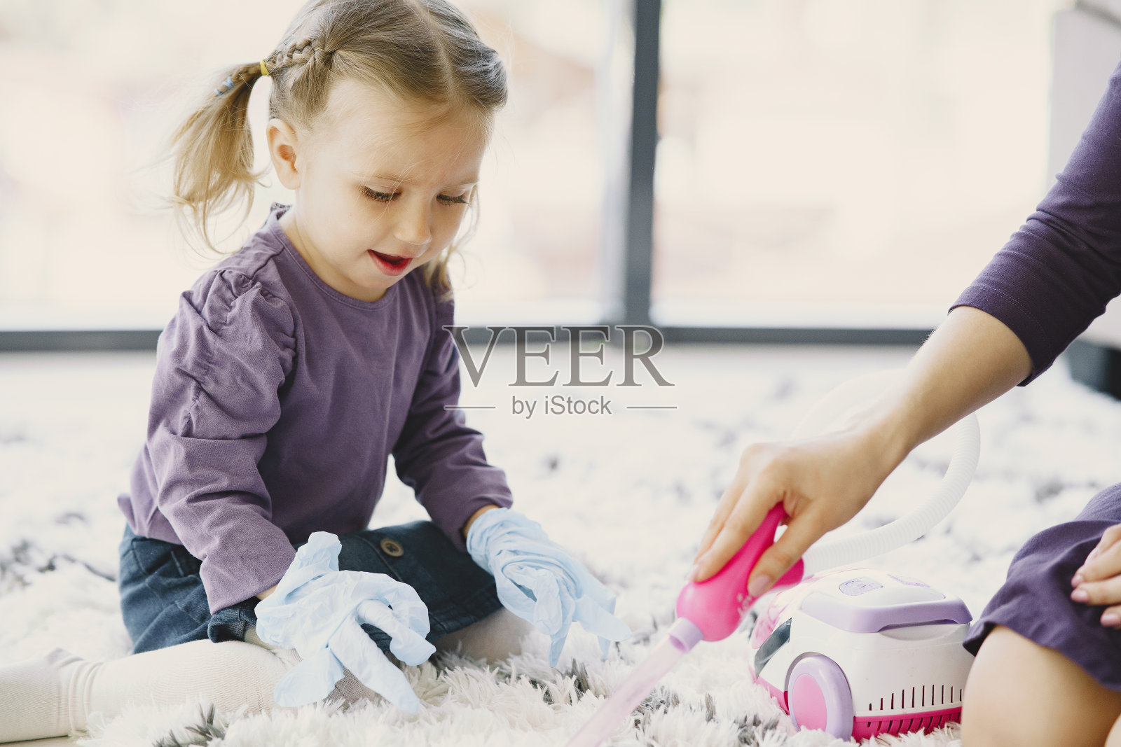小女孩用玩具吸尘器清洁地板照片摄影图片