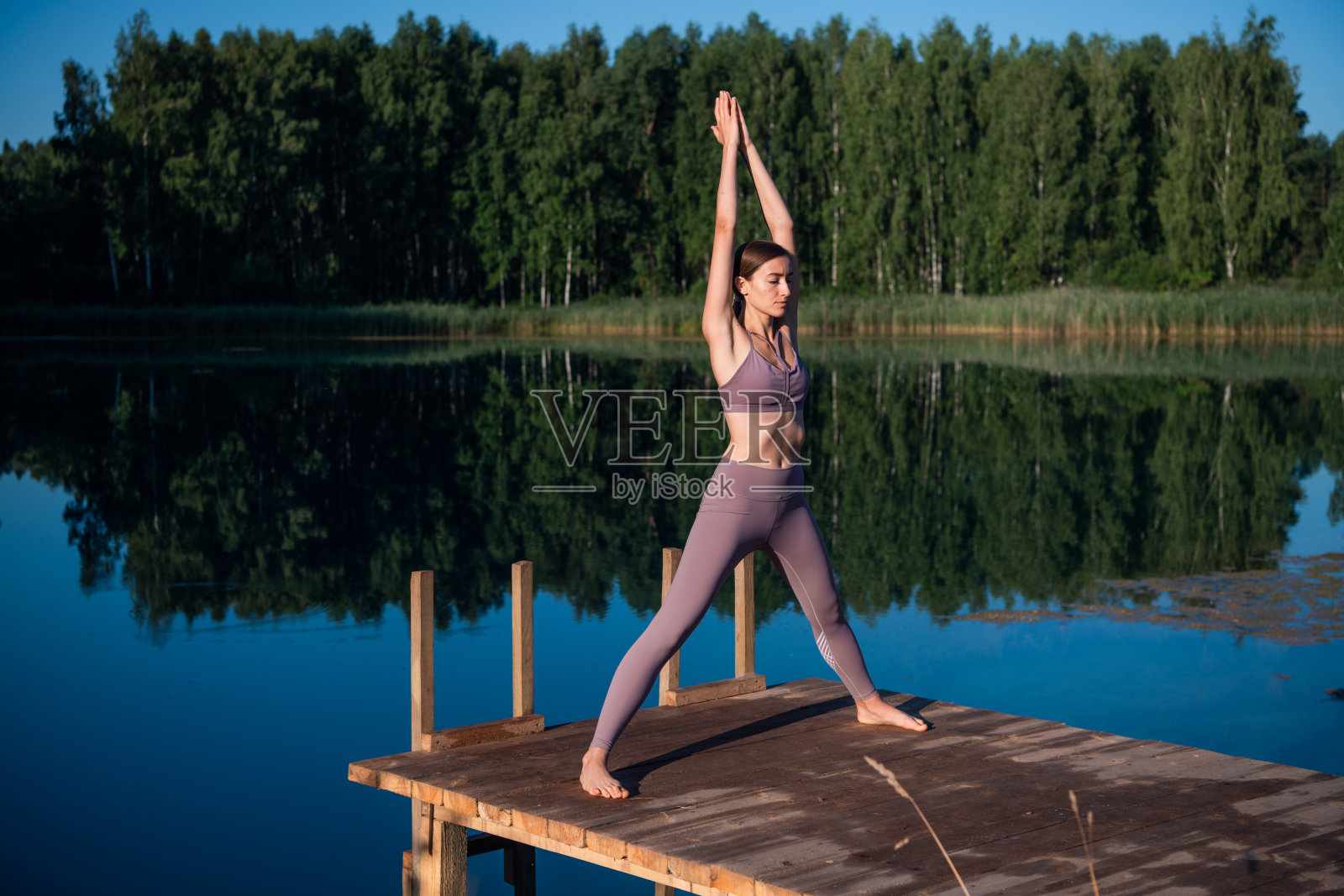瑜伽户外体式练习日落在一个码头在一个湖由运动平静的女孩照片摄影图片