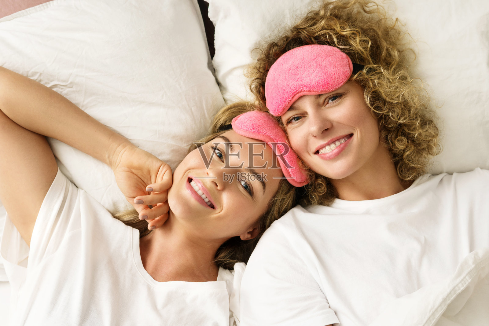两个美丽开朗的女孩躺在床上放松照片摄影图片