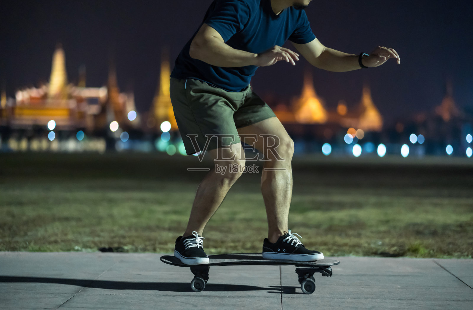 亚洲人在户外公园玩冲浪或滑板，在照片模糊的曼谷大皇宫，泰国，低光，极限运动，健康和运动，时尚的新冠概念照片摄影图片