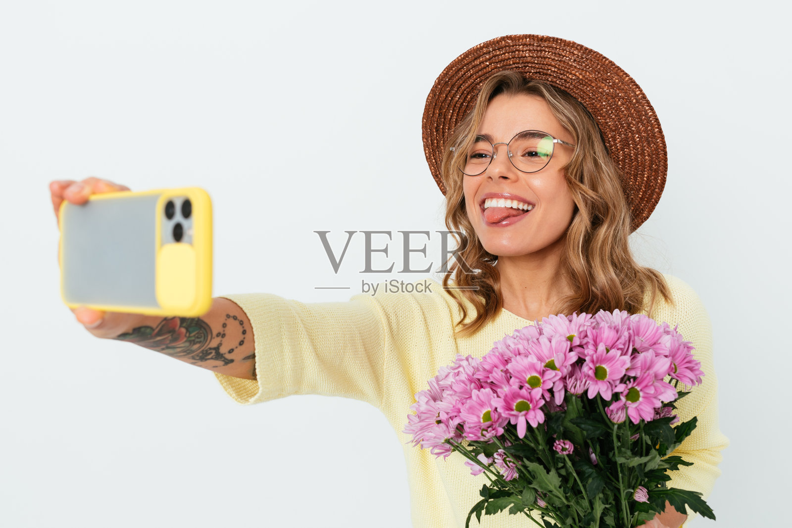 一名兴高采烈的年轻女子手持一束鲜花用智能手机自拍照片摄影图片