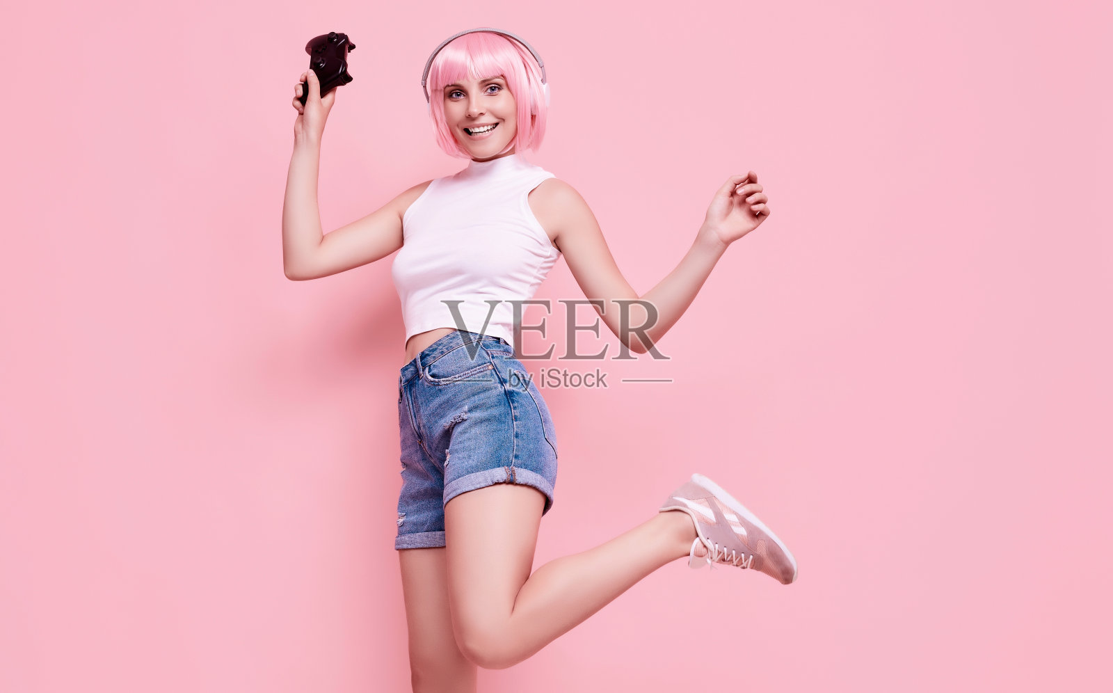 快乐性感的玩家女孩与粉红色的头发玩视频游戏使用操纵杆照片摄影图片
