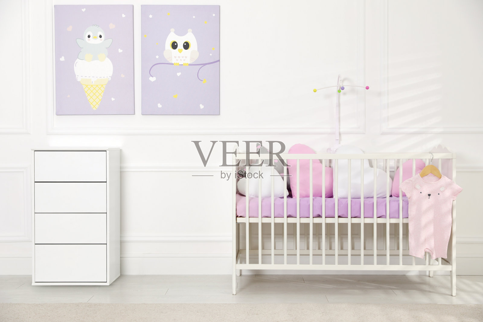 婴儿床和梳妆台靠近墙上的照片在舒适的婴儿房。室内设计照片摄影图片