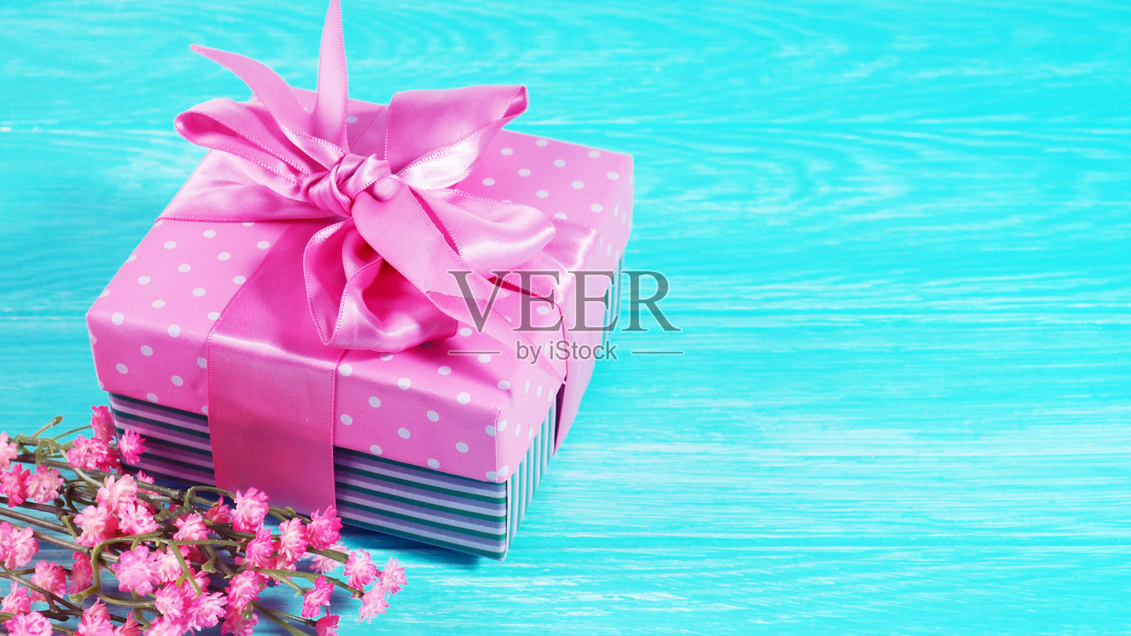 一个礼品盒与一个粉红色的蝴蝶结在一个木制的背景，复制的文本空间照片摄影图片