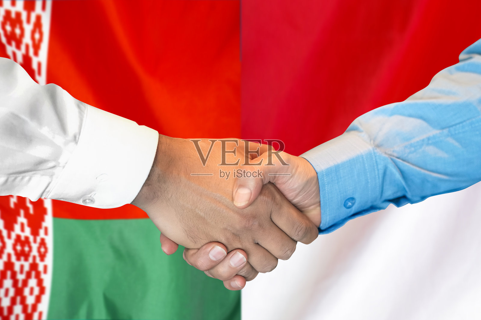在白俄罗斯和印度尼西亚国旗背景下握手。支持的概念。照片摄影图片