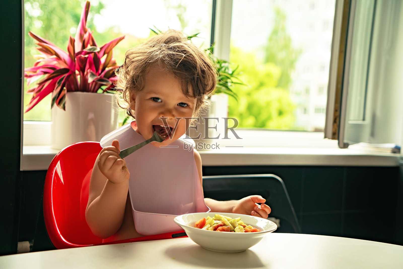 小孩子喜欢在厨房里吃蔬菜沙拉照片摄影图片
