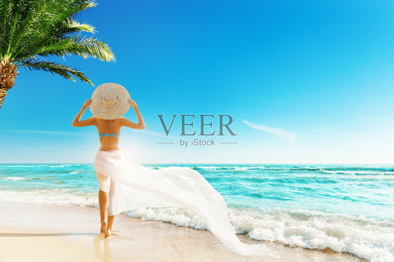 夏日海滩度假。旅行女孩日光浴太阳帽，比基尼，白色飘逸的裙子。女人回头看海洋照片摄影图片
