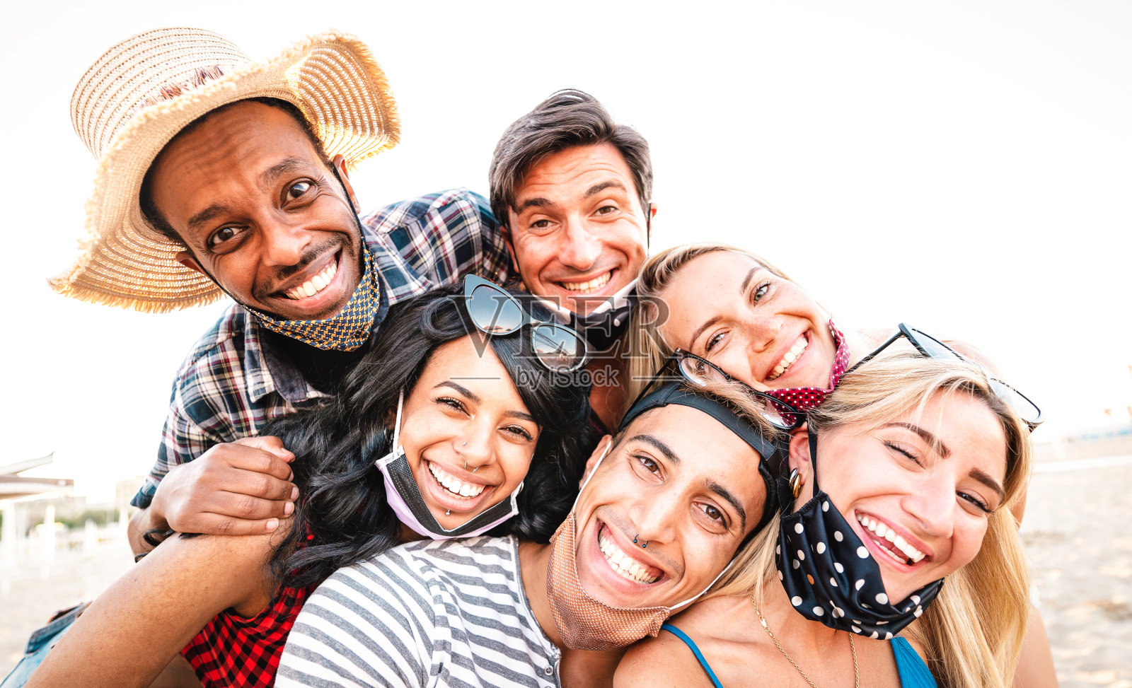 多种族的朋友在开放的面具上自拍微笑-新的正常生活方式的友谊概念，年轻人在封锁重新开放后一起玩-温暖明亮的背光滤镜照片摄影图片