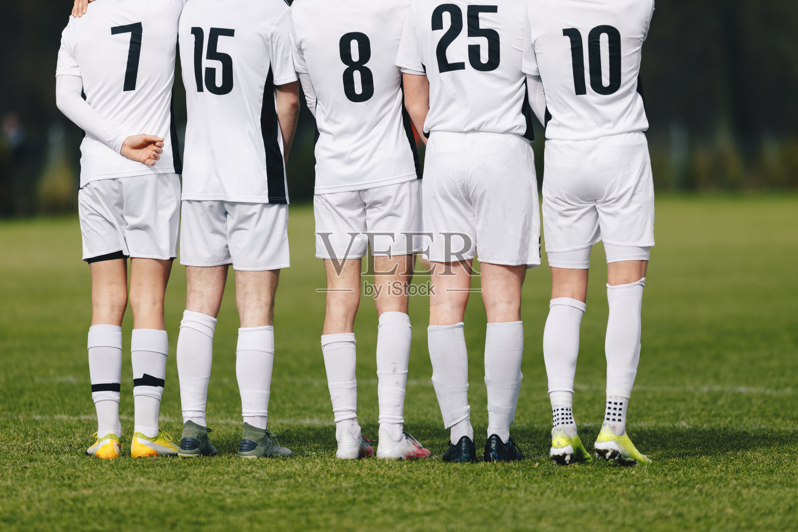 任意球时足球运动员站在墙边。足球运动员身穿白色运动衫，背面印有黑色号码。穿草皮钉鞋的足球运动员。足球队的少年男孩照片摄影图片