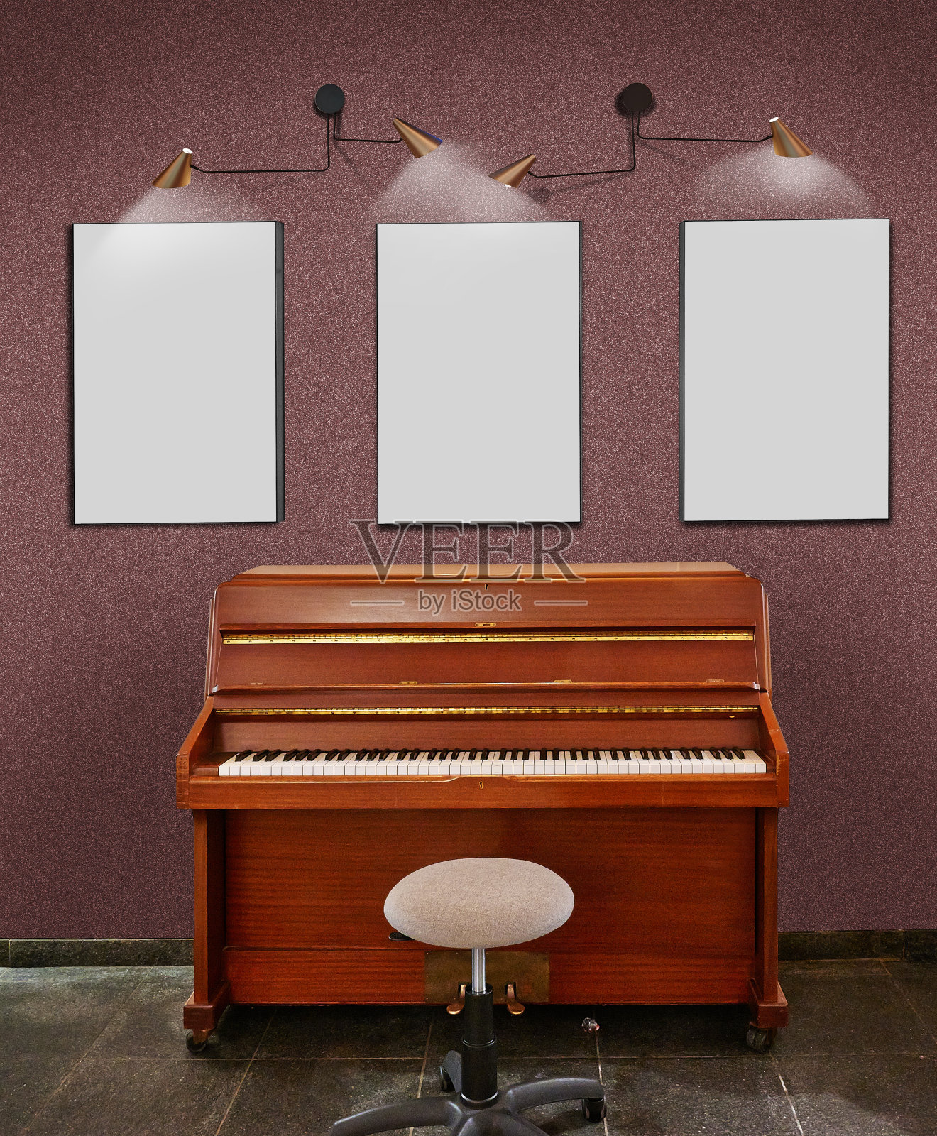 一架老式的立式钢琴，一张凳子和三个空白的框架靠在闪亮的墙上。照片摄影图片
