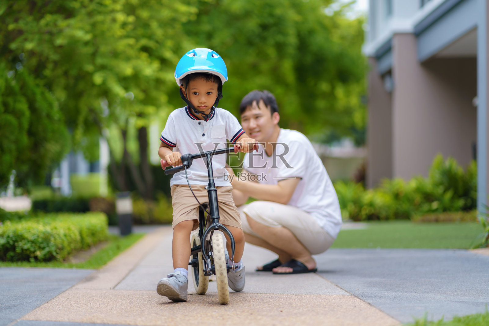 亚洲父亲教他的孩子如何骑自行车在附近的花园，父亲与他们的孩子互动一整天。照片摄影图片