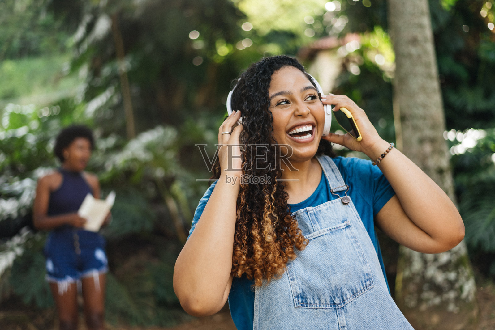 微笑的女人在院子里耳机听音乐照片摄影图片