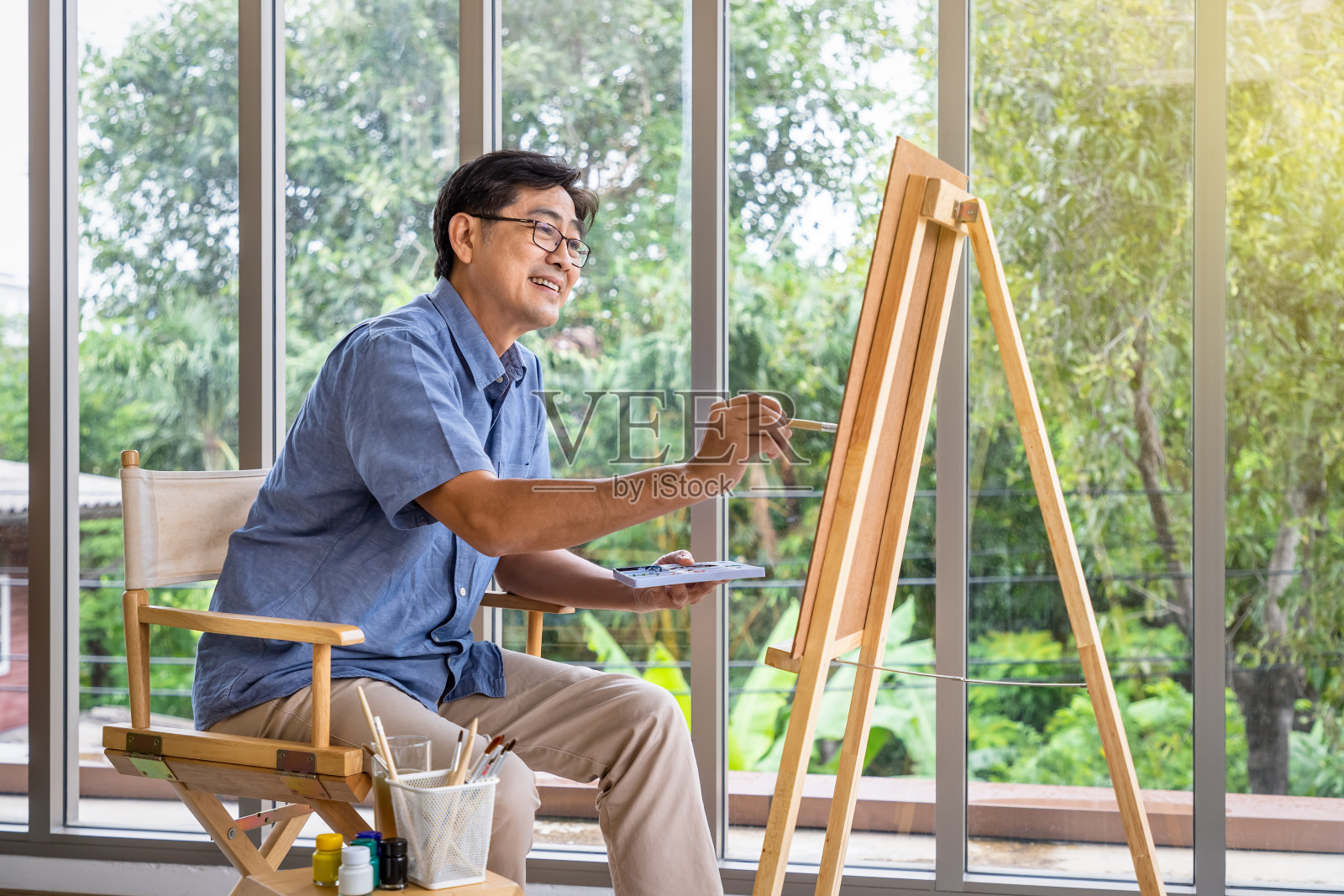 年长微笑的亚洲人用刷子和水彩在画布上作画。快乐退休，活动理念。照片摄影图片