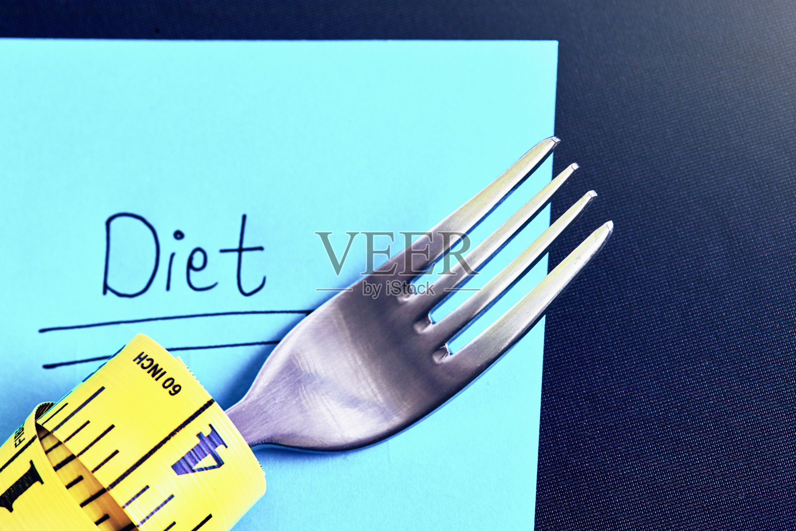 叉子下面用卷尺包着的便利贴上写着“节食”这个词照片摄影图片
