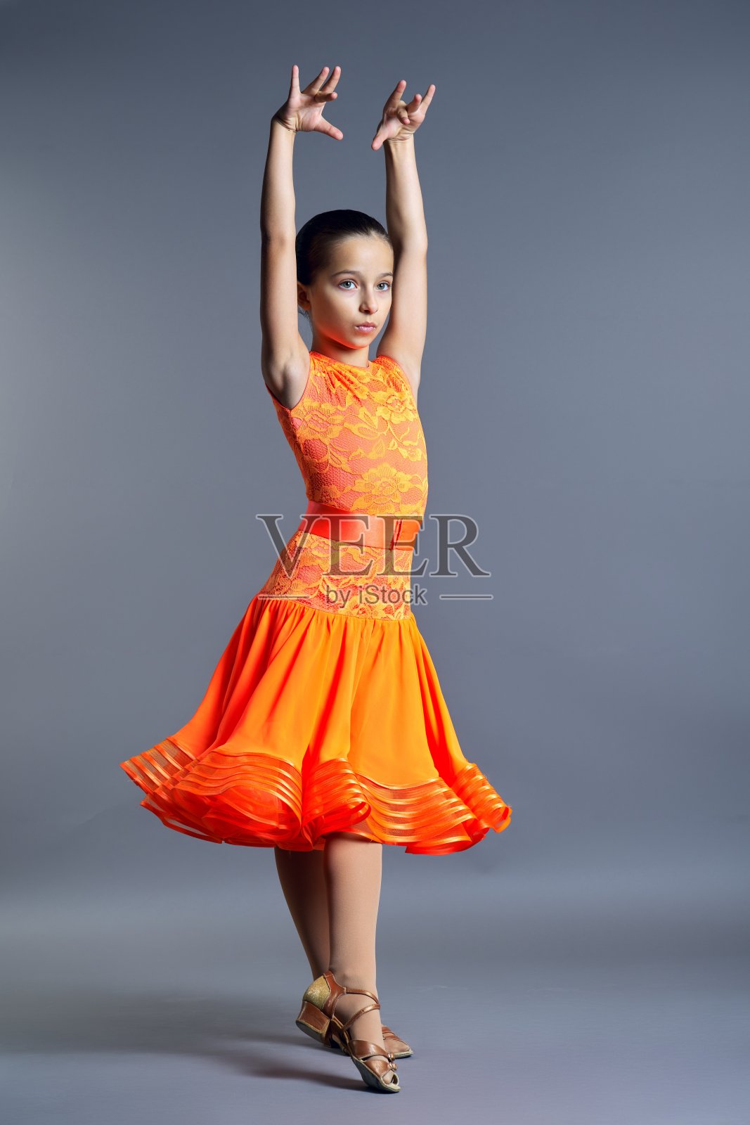 孩子女孩在一个橙色的运动服装摆姿势在舞蹈运动在灰色的背景照片摄影图片