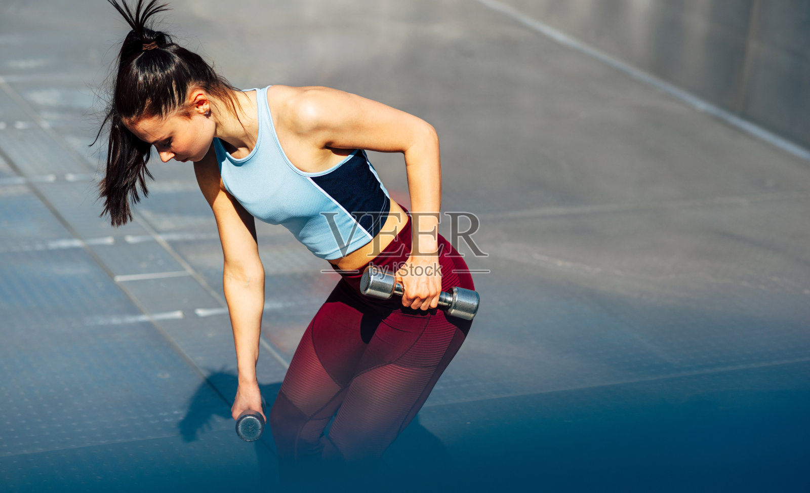 一个女运动员在户外用哑铃做运动的水平侧视图。照片摄影图片
