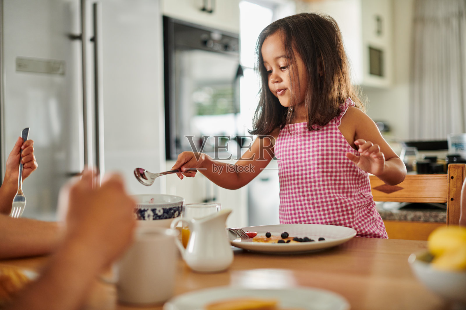 一个可爱的小女孩和她的家人在家里吃煎饼当早餐照片摄影图片
