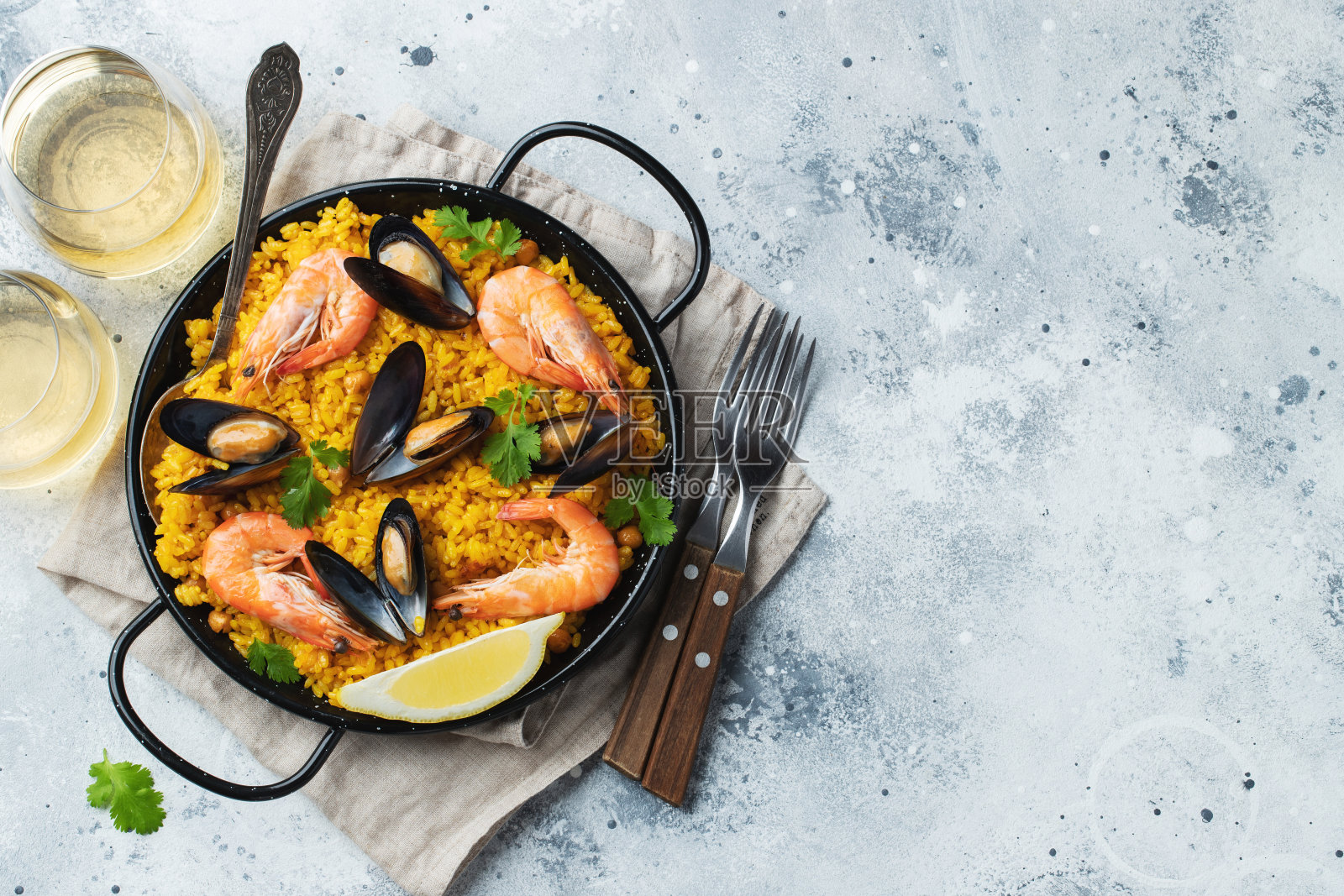 传统的西班牙海鲜饭与鹰嘴豆，虾，贻贝，鱿鱼在浅灰色混凝土背景。顶部视图与复制空间照片摄影图片