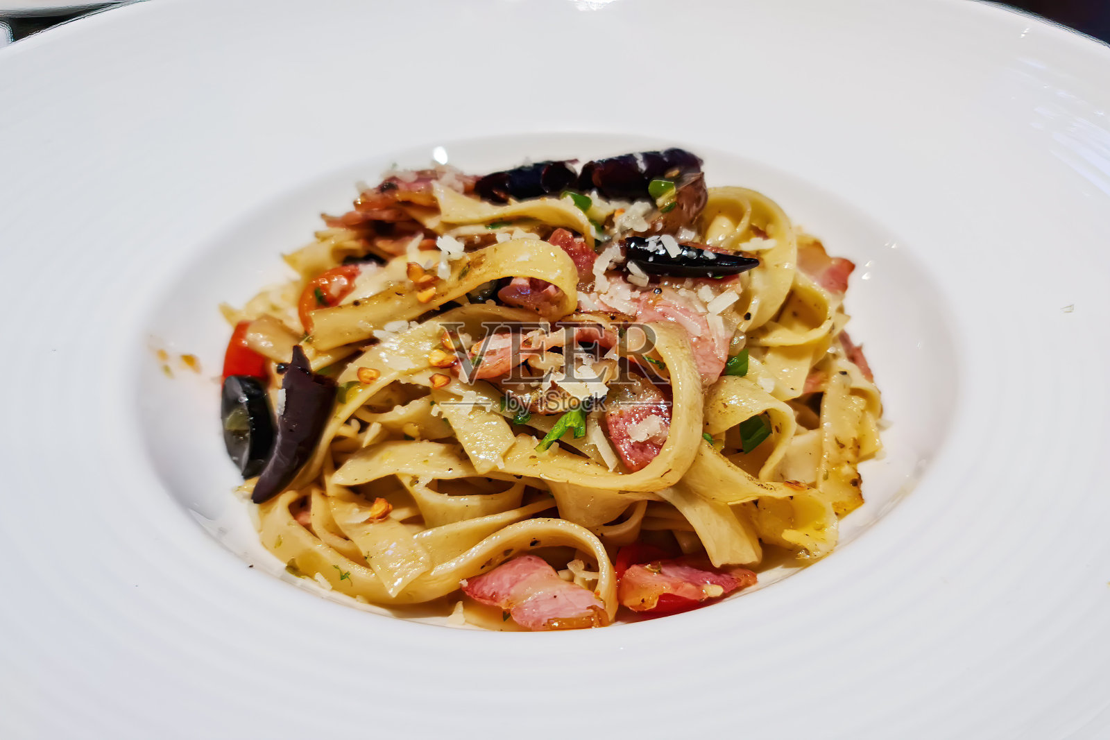 意大利面，芝士酱，培根，辣椒和新鲜的配料混合在白色的盘子背景照片摄影图片