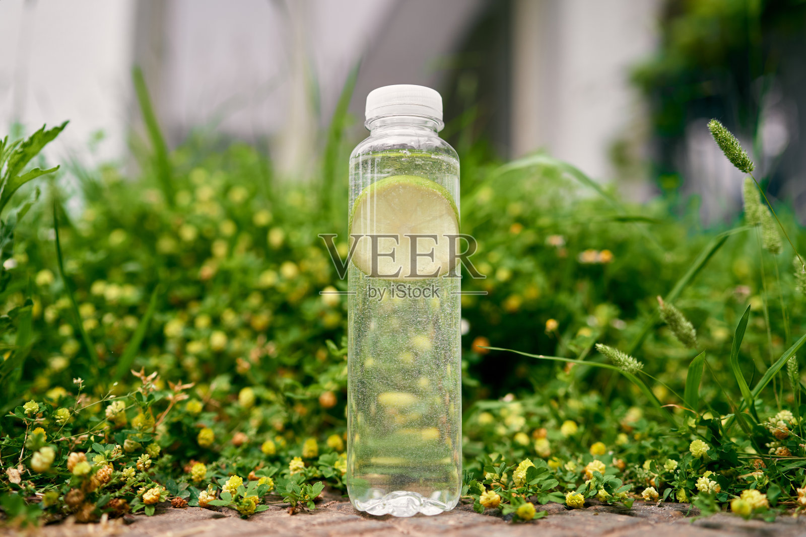 一瓶柠檬水放在一片绿油油的草地上，四周是野花照片摄影图片