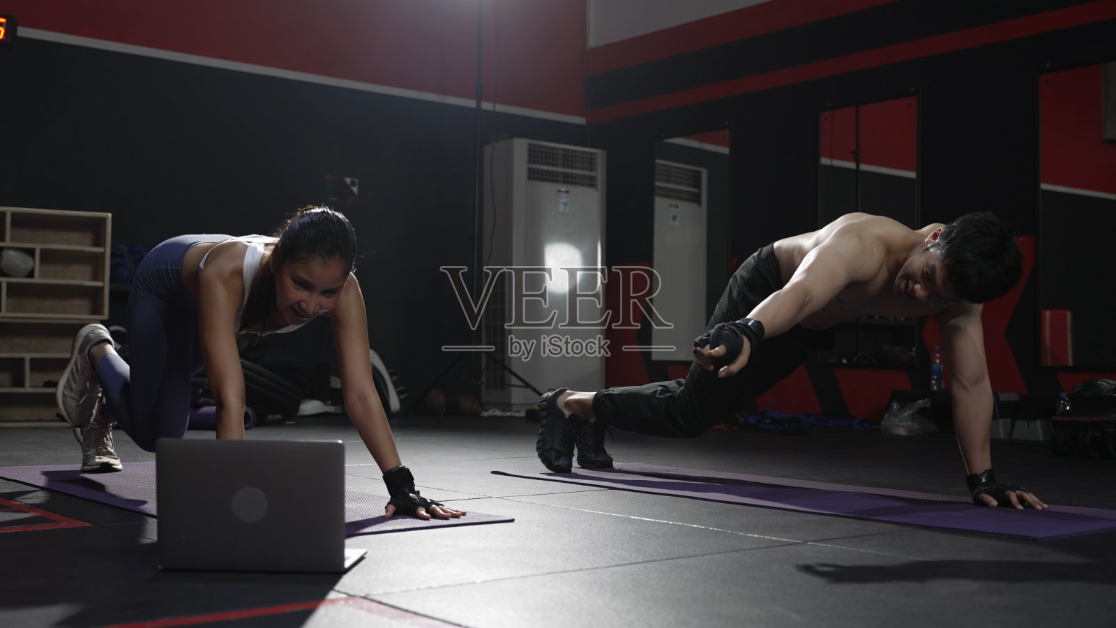 运动夫妇有氧运动与在线视频笔记本电脑在健身房里健身身体健康的生活方式运动员肌肉建设强壮的概念。照片摄影图片